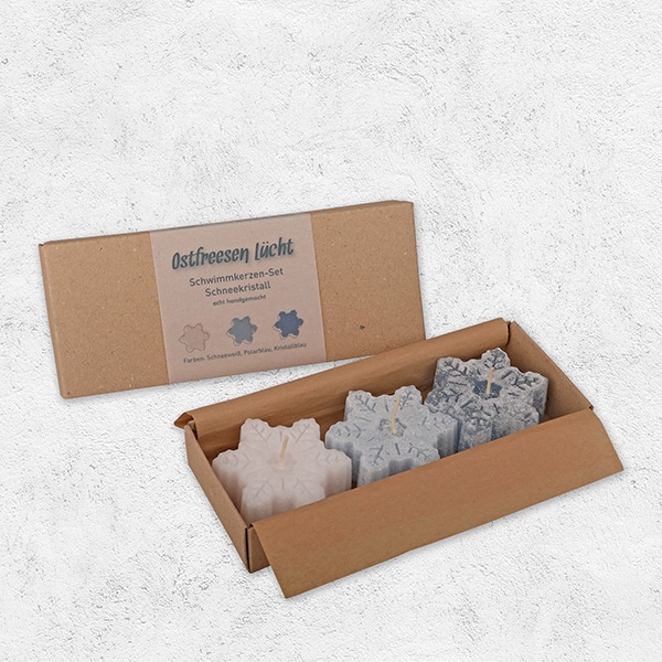 Drei Schwimmkerzen in Form von Schneekristallen in einer Verpackung aus Pappe.