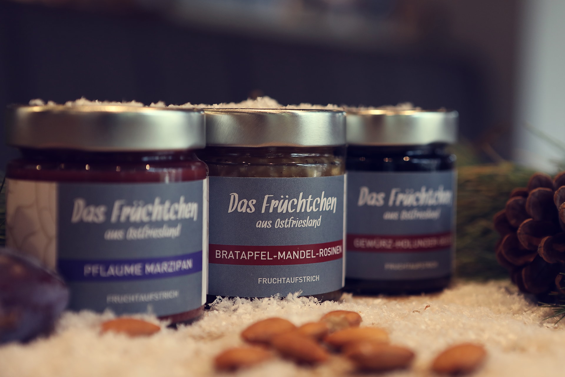 Drei Gläser Fruchtaufstrich stehen auf einem Holzbrett.
