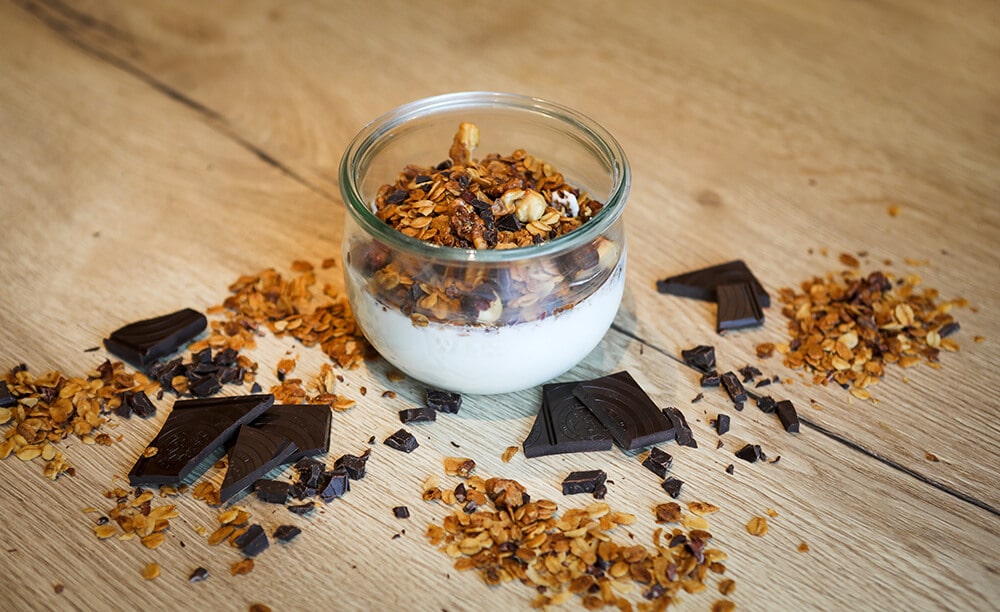 Ein Glas mit Joghurt und Knuspermüsli mit Kakaostückchen.
