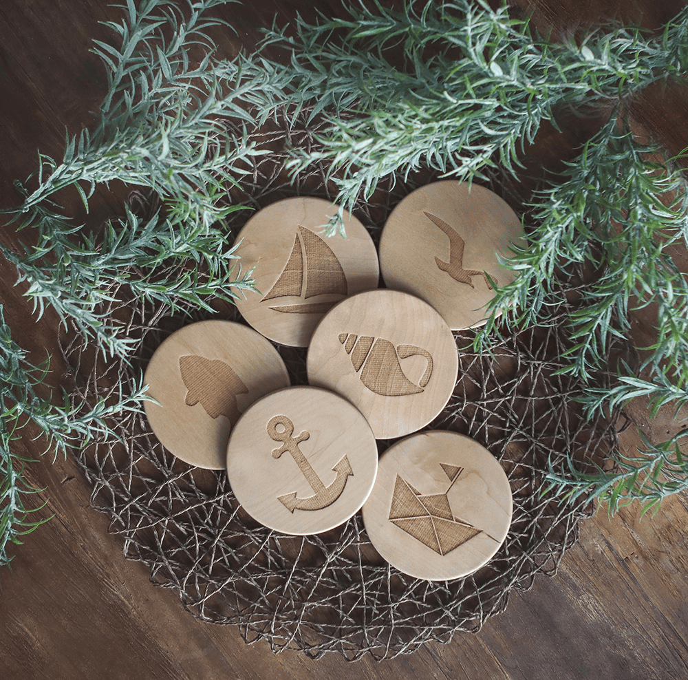 Unterschiedliche Untersetzer aus Holz mit maritimen Motiven, dekoriert auf einem Tisch.