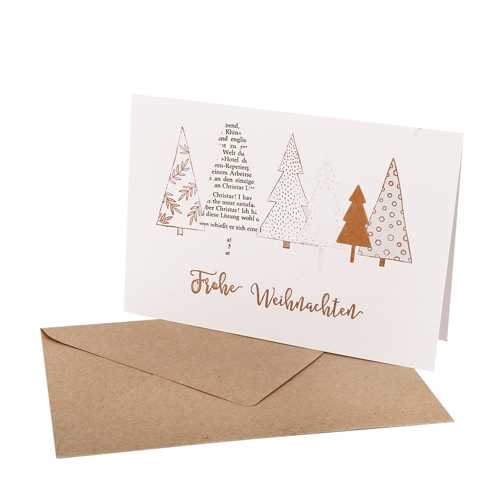 Handgefertigte Klappkarte mit aufgeklebten Tannenbäumen aus Papier und dem Spruch Frohe Weihnachten, mit braunem Umschlag.