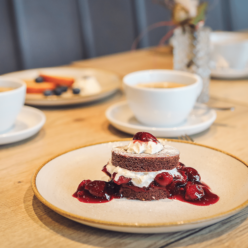 Schokoladenkuchen mit Schuss, als kleine Schwarzwälder-Kirsch-Torte angerichtet und mit einer Tasse Kaffee.
