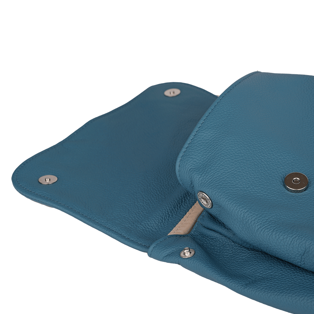 Die Druckknöpfe eines kleinen Rucksacks aus Leder in der Farbe rauchblau.