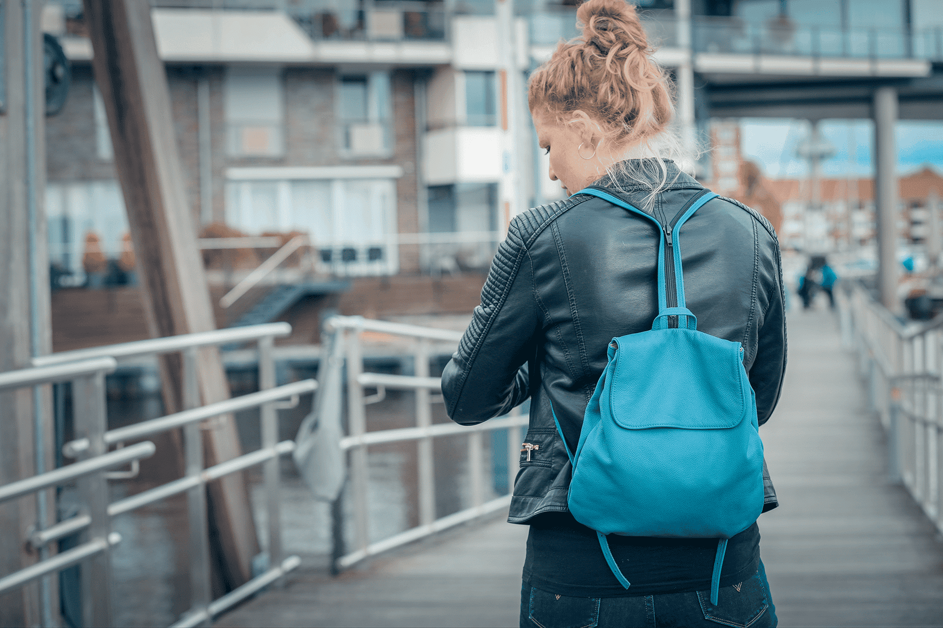 Eine Person trägt einen kleinen Rucksack aus Leder in der Farbe rauchblau auf dem Rücken.