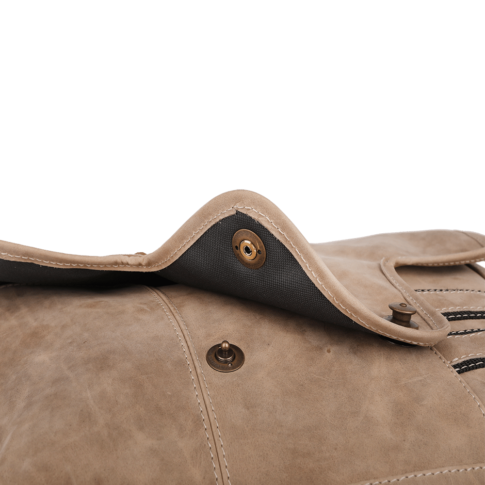 Druckknopf einer Umhängetasche aus Leder in der Farbe beige.