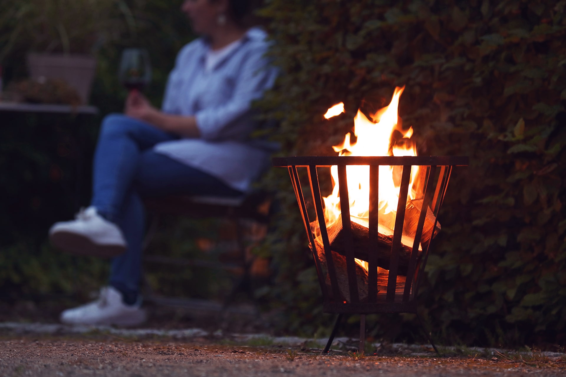 Ein brennender Feuerkorb in einem Garten.