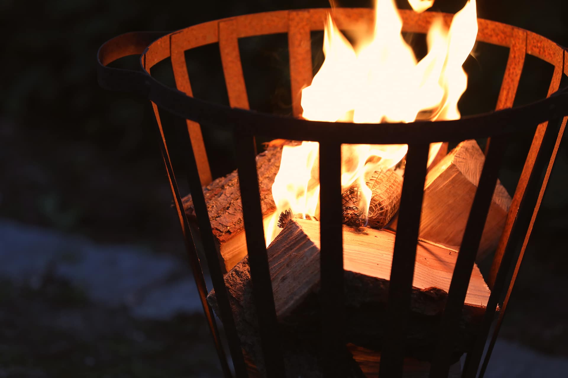 Ein brennender Feuerkorb in einem Garten.