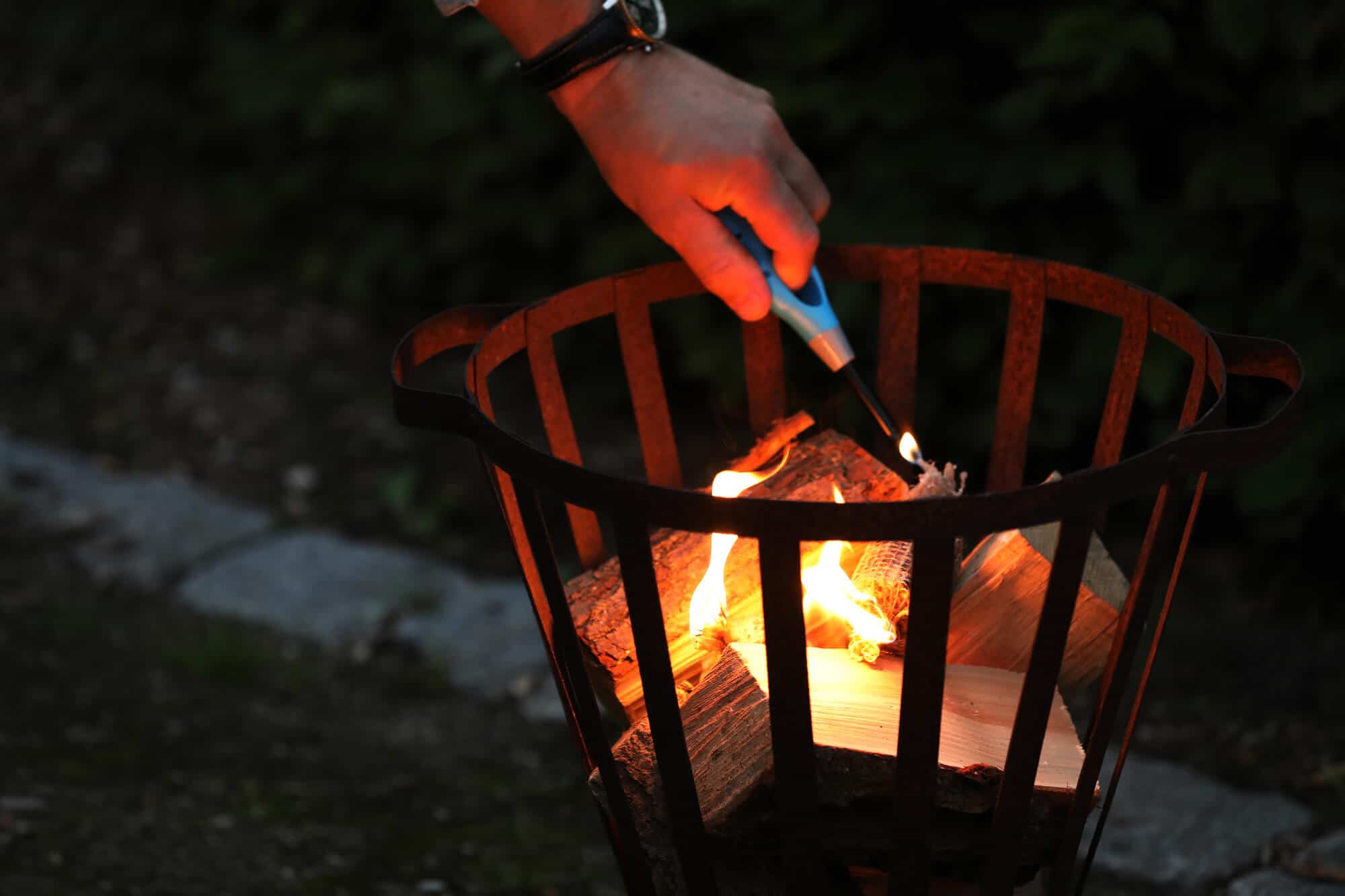 Eine Person zündet Holz in einem Feuerkorb mit den Anzündern Füür Bontjes an.