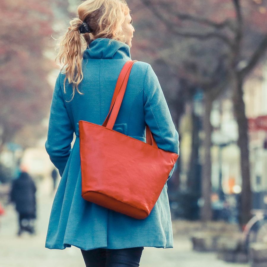 middenmang Ledertasche in rot Modell die Großartige getragen von einer blonden Frau mit dem Rücken zur Kamera, in einem türkisfarbenem Mantel