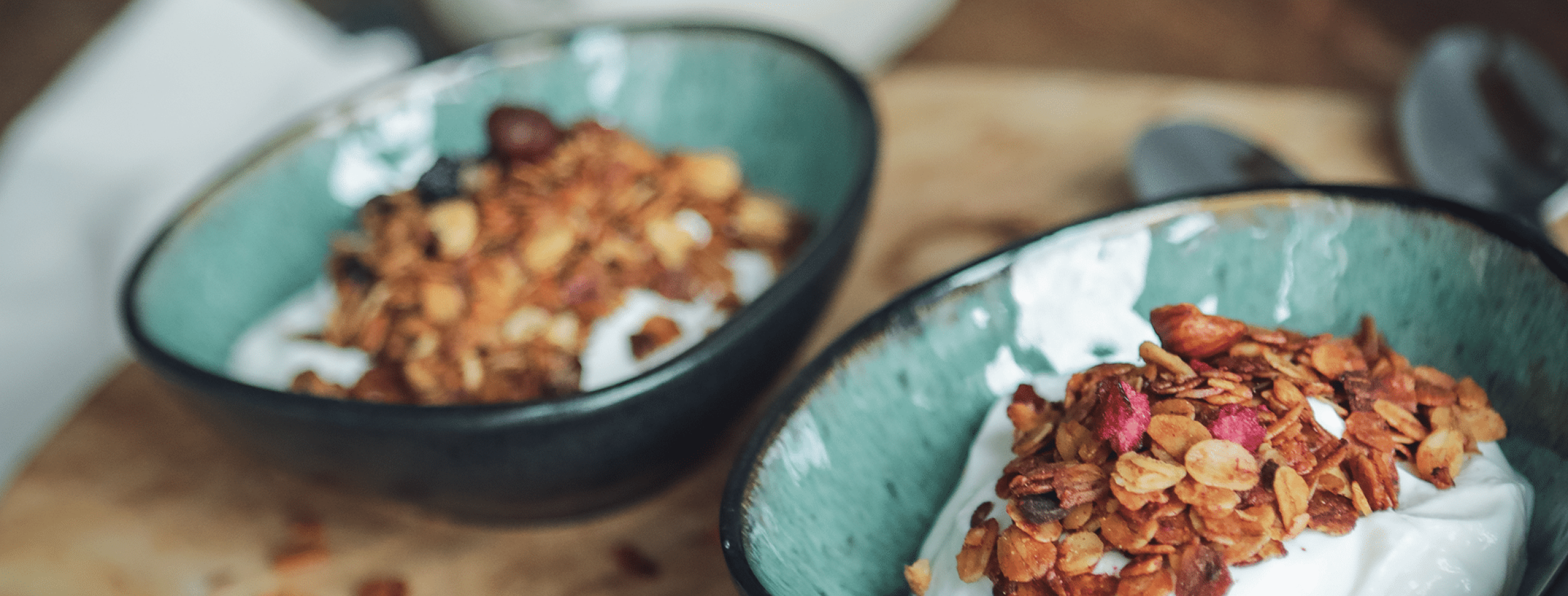 Zwei Sorten Knuspermüsli in Keramikschalen angerichtet.